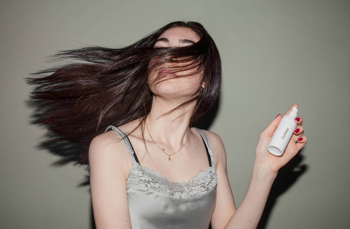 Woman applying hair styling mist to damp hair before blow-drying