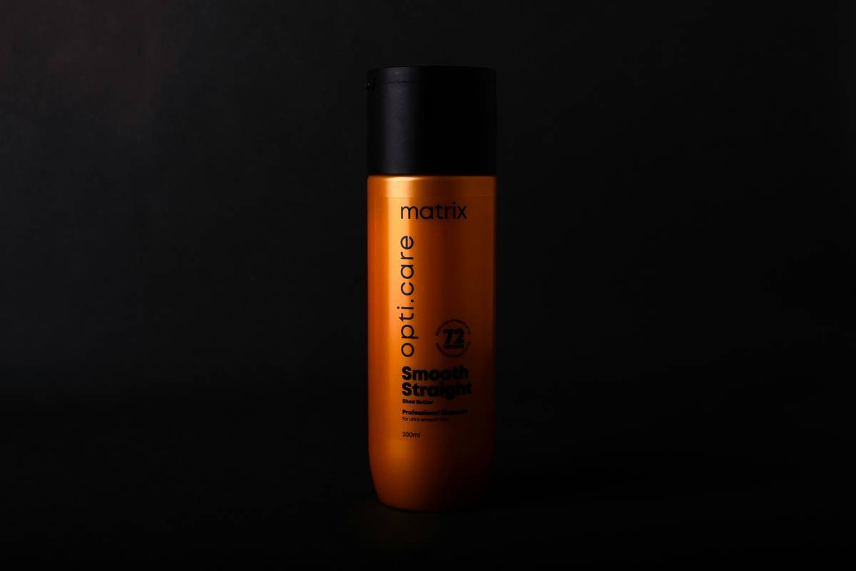 Close-up of hand applying hair care styling gel to damp curly hair for definition and hold