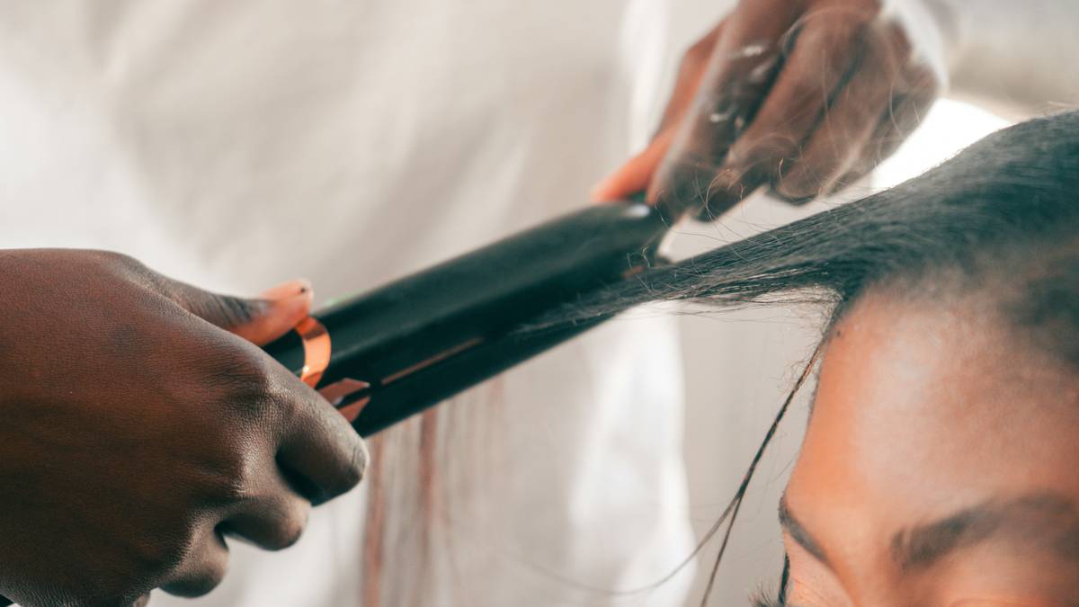 Woman using a professional hot air brush on shoulder-length brown hair, creating smooth volume near roots