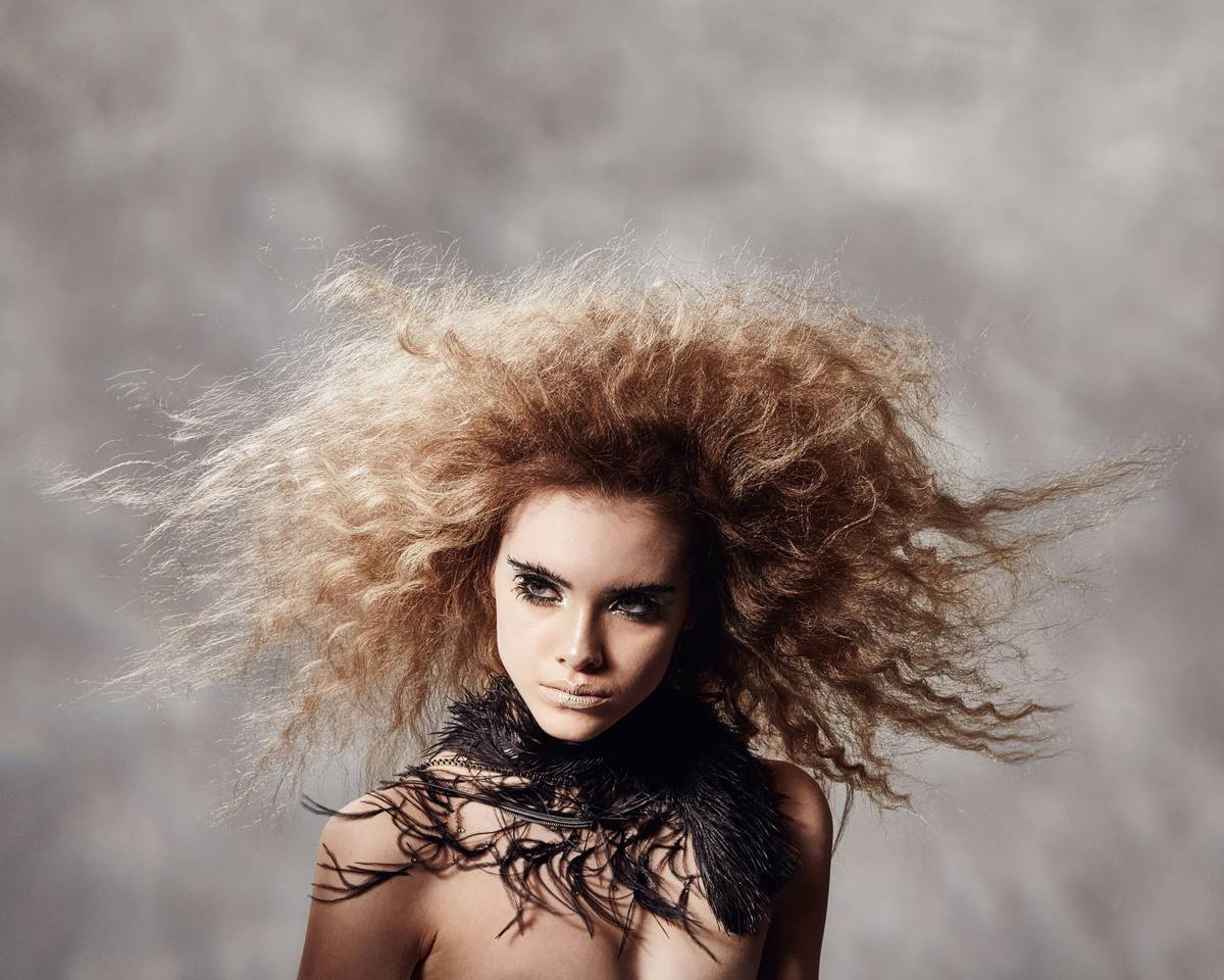Close-up of hand applying hair styling powder to roots of dark brown hair for volume